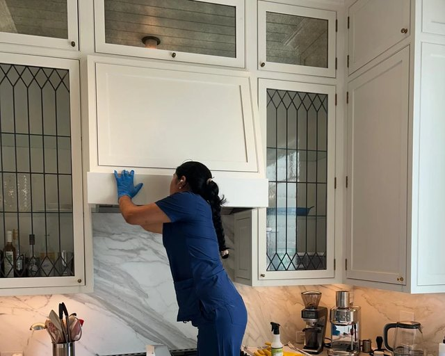 Royal Glow team member detail-cleaning a kitchen from a step ladder