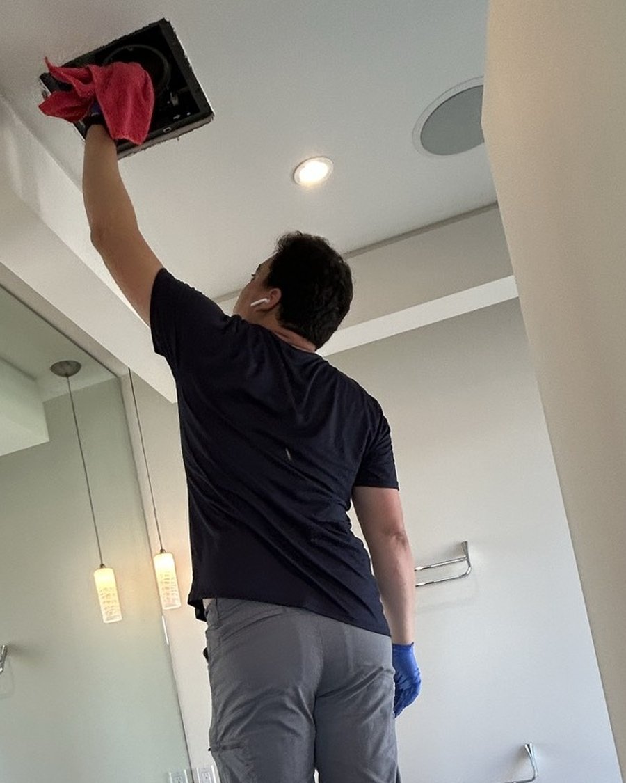 Royal Glow Cleaning team member cleaning a ceiling vent high overhead