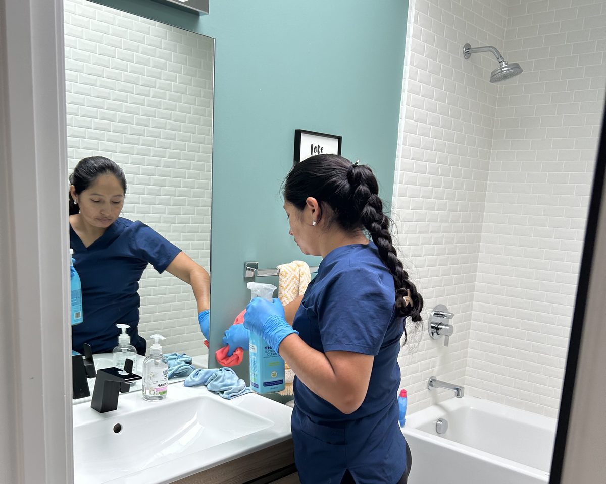 Two Royal Glow cleaners detailing a bathroom vanity and tub in a San Mateo home