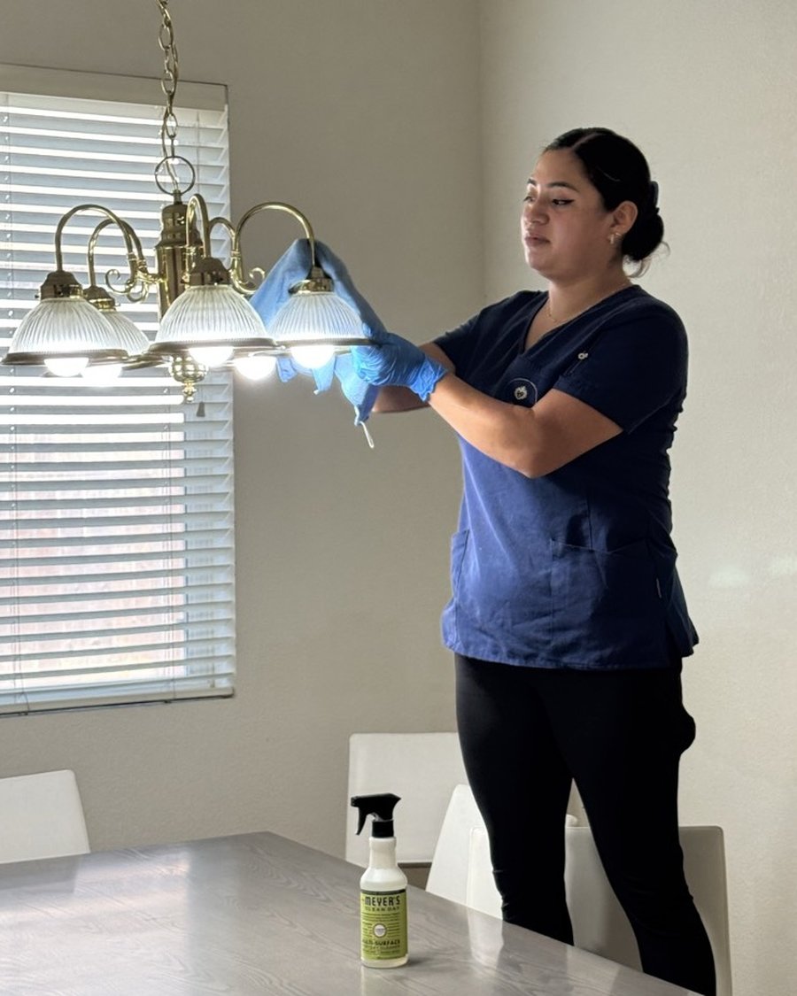 Royal Glow Cleaning team member dusting a chandelier