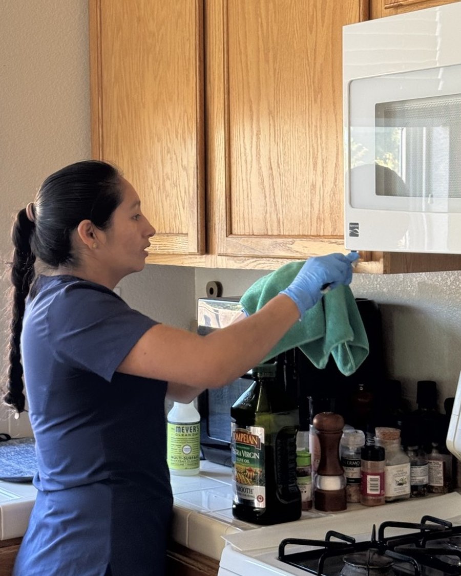 Royal Glow Cleaning team member cleaning a kitchen microwave